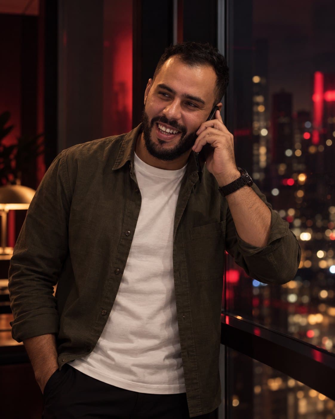 Ayoub Jouini laughing on a phone call by a window at night